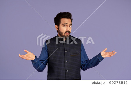 Who knows. Confused Indian guy shrugging shoulders on violet background Who knows. Confused Indian guy shrugging shoulders on violet background 69278612