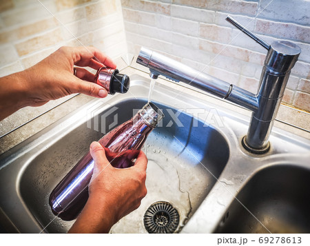 hand with aluminum eco friendly bottle pour tap water from the sink to reduce plastic usage 69278613
