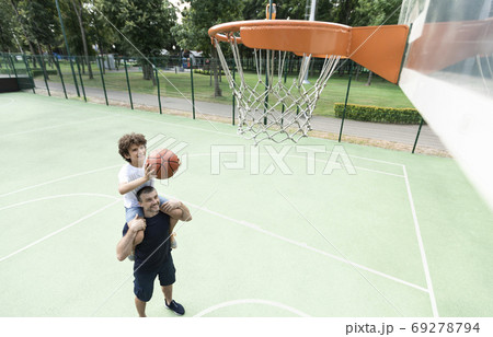 Happy daddy helps his son to score a basket 69278794