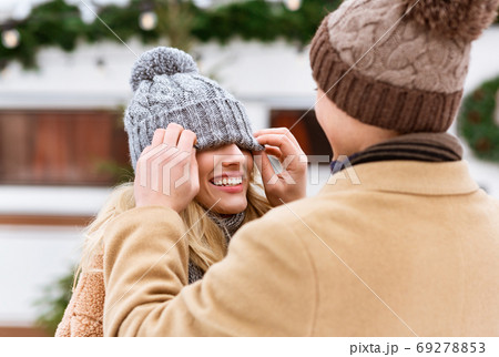 Romantic couple having fun outdoors in winter, man playing with girlfriend's hat 69278853