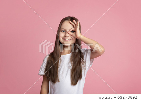 Everything is cool. Smiling kid doing ok sign with hand on eye looking through fingers 69278892