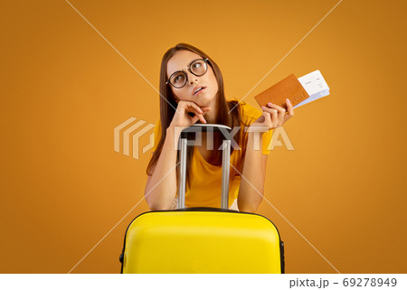 Confused young woman in sunglasses holding passport and tickets Confused young woman in sunglasses holding passport and tickets 69278949
