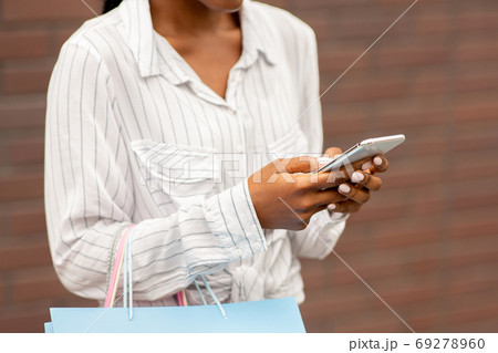 Mega discounts in store. African american millennial woman with colors bags typing on smartphone 69278960