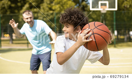 Joyful dad playing basketball with his son 69279134