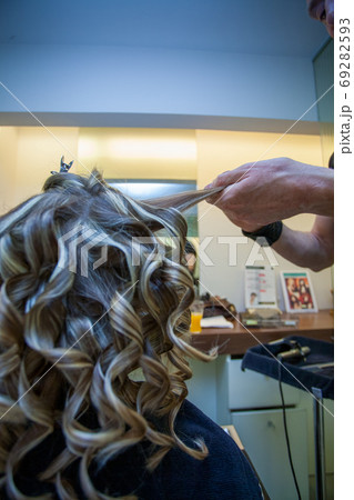Hairdresser curling a blonde woman's hair 69282593