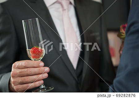 Man in suit holding a glas of sparkling wine or champagne and strawberry Man in suit holding a glas of sparkling wine or champagne and strawberry 69282876