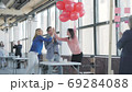 A young woman manager walks in the office with red balloons and congratulates a colleague. Happy birthday to colleagues. Coworking. Modern trendy office interior in a loft style 69284088