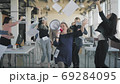 Colleagues perform a hand dance in the office during a break. A man rolls an employee in a chair, colleagues join in, scatter money, dance and shout into a megaphone. Fun athmosphere. 69284095