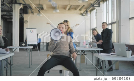 A young woman in an office throws a phone and rolls a colleague a man on a chair. All office employees join and dance together. Managers scatter money, paper and have fun. Front video. A young woman in an office throws a phone and rolls a colleague a man on a chair. All office employees join and dance together. Managers scatter money, paper and have fun. Front video. 69284103