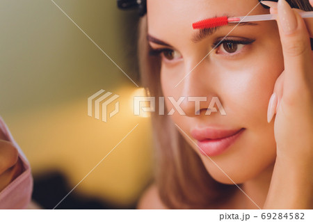 Young woman having professional eyebrow correction procedure in beauty salon. 69284582