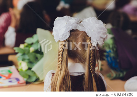 Hair braided in two braids with white bows hairstyle schoolgirl holiday. Hair braided in two braids with white bows hairstyle schoolgirl holiday. 69284800