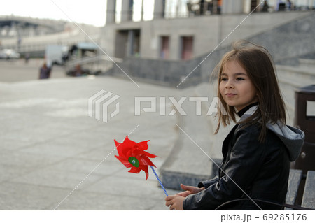 Little girl in urban surroundings with red wind spinner Little girl in urban surroundings with red wind spinner 69285176