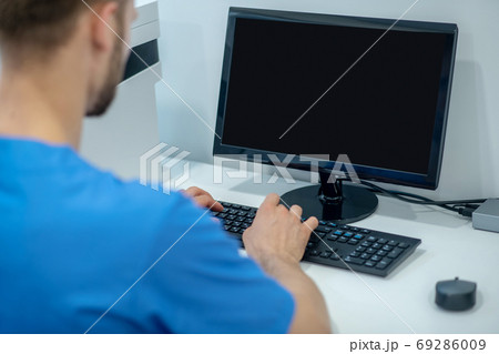 Male medic working at computer his back to camera 69286009