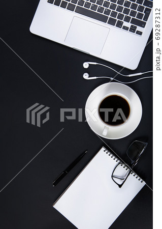 Black office desk with laptop, smartphone, pen, glasses and cup of coffee.  69287312