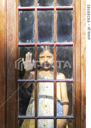 Brunette girl behind wooden and glass door Brunette girl behind wooden and glass door 69289383