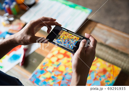 描いた絵をスマホで撮る画家の写真素材