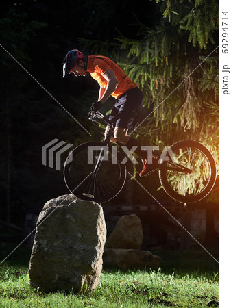 Biker performing tricks in the park Biker performing tricks in the park 69294714