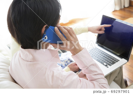 パソコンを見ながら電話する夫婦 パソコンを見ながら電話する夫婦 69297901