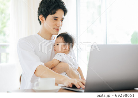 赤ちゃんを抱きながらテレワークをする男性 赤ちゃんを抱きながらテレワークをする男性 69298051