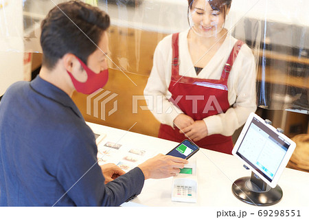 感染症対策をした店でキャッシュレス決済をする男性客と女性店員 感染症対策をした店でキャッシュレス決済をする男性客と女性店員 69298551