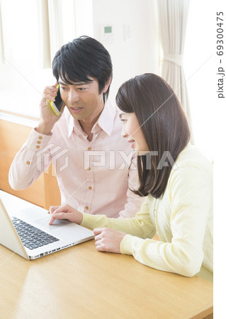 パソコンを見ながら電話する夫婦 パソコンを見ながら電話する夫婦 69300475