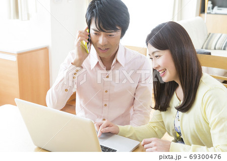 パソコンを見ながら電話する夫婦 パソコンを見ながら電話する夫婦 69300476