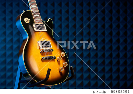 Sunburst electric guitar standing over acoustic foam panel background Sunburst electric guitar standing over acoustic foam panel background 69302591