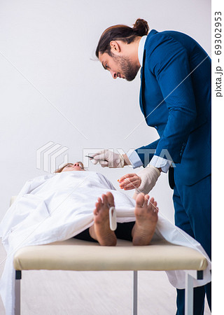 Police coroner examining dead body corpse in morgue Police coroner examining dead body corpse in morgue 69302953