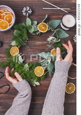 Woman's hands in knitted sweater holding hand made Christmas wreath 69303548