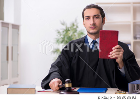 Young male judge working in courthouse 69303892
