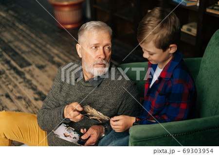 Top view of handsome gray-haired grandfather showing photo to his grandson Top view of handsome gray-haired grandfather showing photo to his grandson 69303954