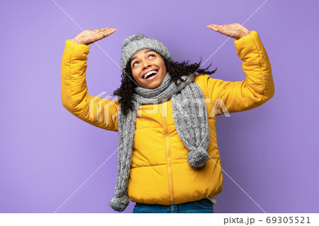 Cheerful Black Girl Holding Invisible Object Above Head, Purple Background Cheerful Black Girl Holding Invisible Object Above Head, Purple Background 69305521