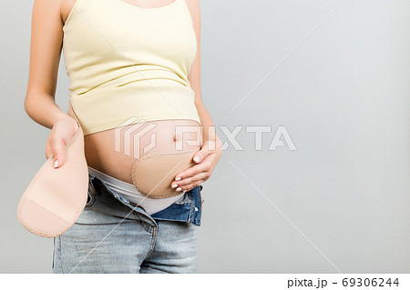 Cropped image of young pregnant woman dressing pregnancy bandage 69306244