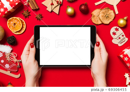 Top view of woman holding tablet in her hands on red background Top view of woman holding tablet in her hands on red background 69306455