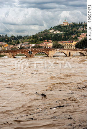 Ponte Pietra - Stone bridge and Adige river in flood in Verona Italy 69307471