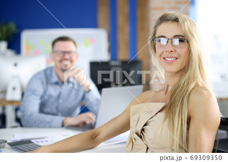 Businesswoman and businessman in office are sitting at desk and smiling 69309350