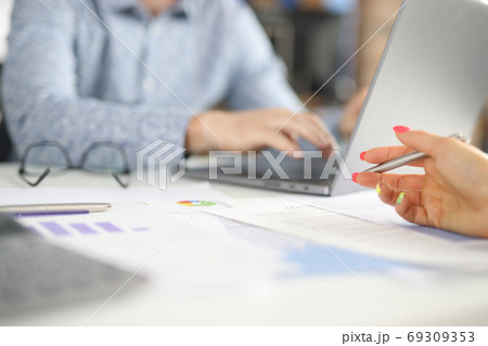 Workplace in office man sits behind laptop female hand holds pen over commercial charts. Workplace in office man sits behind laptop female hand holds pen over commercial charts. 69309353