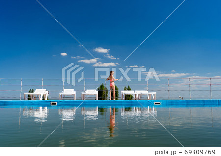 rear view. girl in swimsuit between sun loungers 69309769