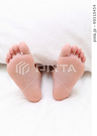 ベッドで眠る女の子の素足の写真素材