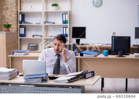Young male employee unhappy with excessive work Young male employee unhappy with excessive work 69310604