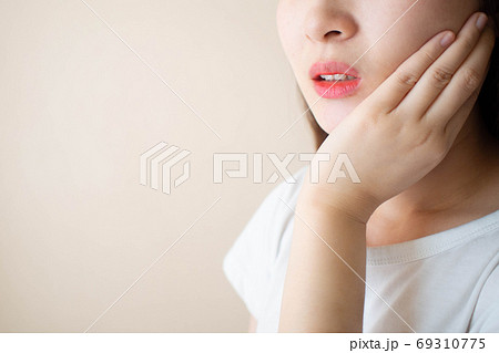 Young woman suffering from toothache over white background. Cause of tooth pain include tooth decay, inflammation, dental abscess, gum disease or sensitive teeth. Dental health concept. 69310775