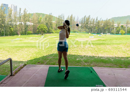 Asian golfer woman swing golf ball practice at golf driving rang 69311544