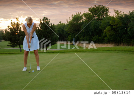 Lady Focused On Hitting Ball Into Golf Hole . 69313314