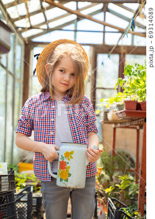 Adorable small girl kid in hat watering seedlings Adorable small girl kid in hat watering seedlings 69314089