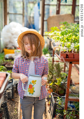 Adorable small girl kid in hat watering seedlings Adorable small girl kid in hat watering seedlings 69314298