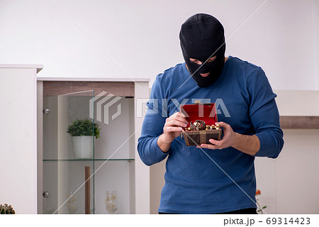 Male robber stealing valuable things from the house Male robber stealing valuable things from the house 69314423