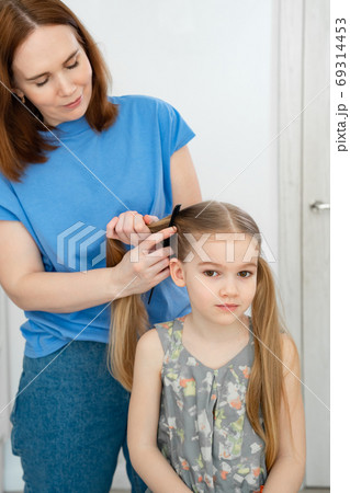 mom makes ponytails of her little daughter 69314453