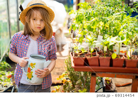 Adorable small girl kid in hat watering seedlings Adorable small girl kid in hat watering seedlings 69314454