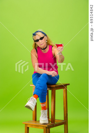 Senior woman in ultra trendy attire isolated on bright green background 69314842