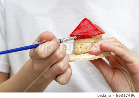 Little girl paints the house from clay or salty 69317496